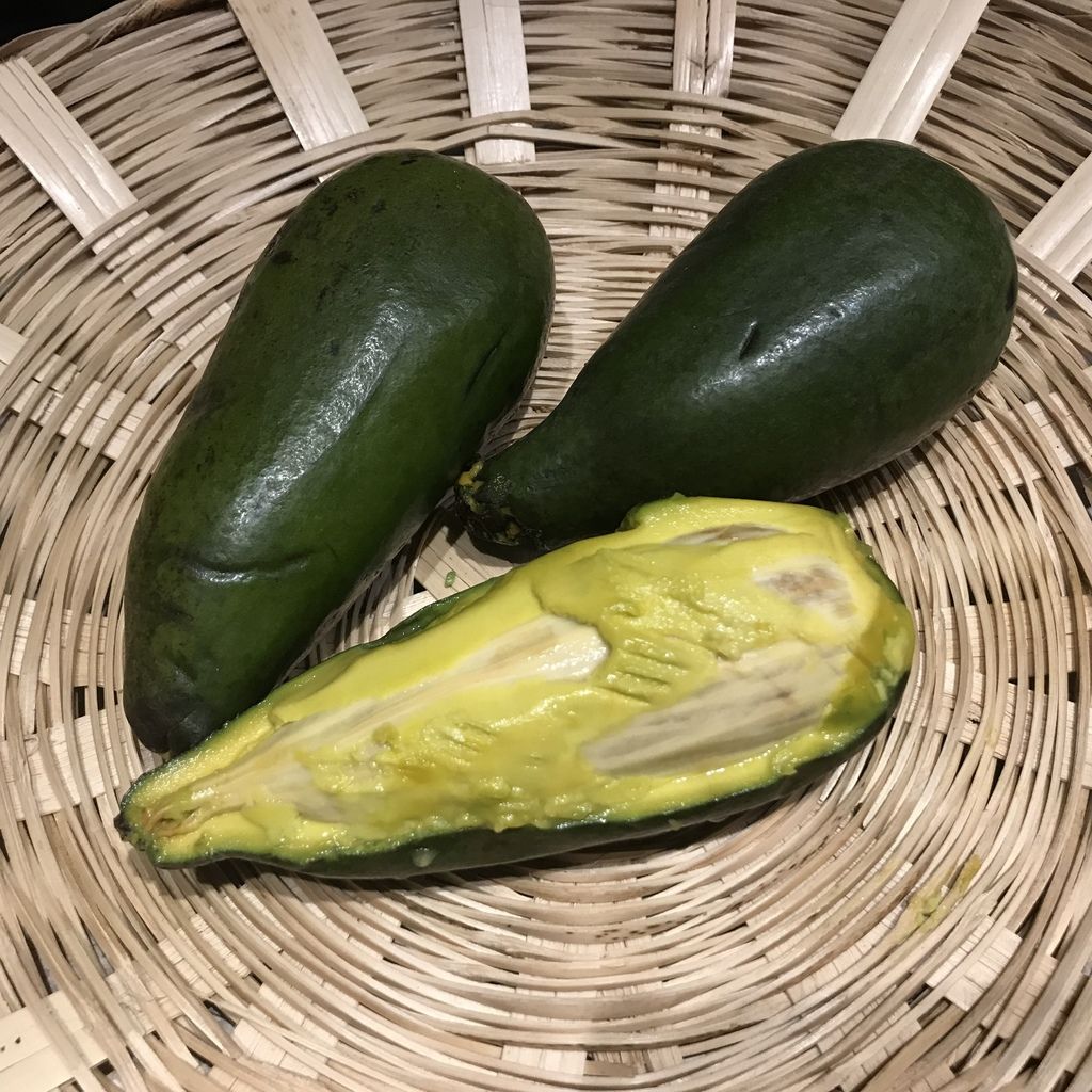 Dos frutos enteros de anayo y uno partido, con la pulpa clara, en una canasta.