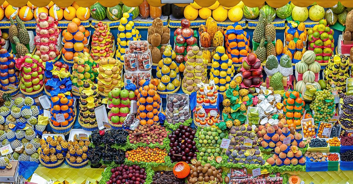 Puesto de mercado con frutas acomodadas en hileras, entre ellas mazorcas de cacao.