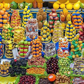 Puesto de mercado con frutas acomodadas en hileras, entre ellas mazorcas de cacao.