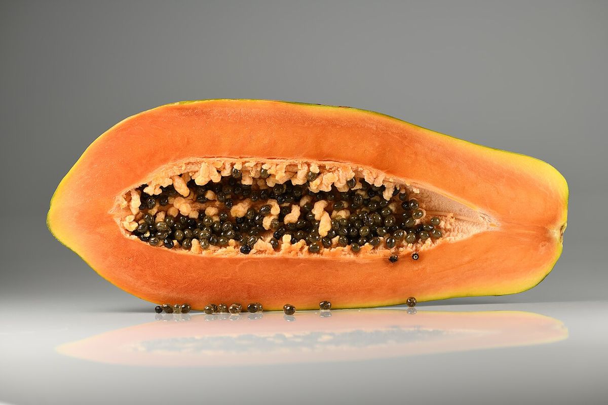 Papaya madura partida a la mitad, con la pulpa naranja y las semillas negras.