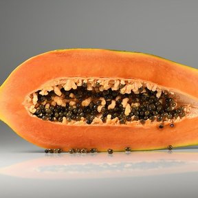 Papaya madura partida a la mitad, con la pulpa naranja y las semillas negras.