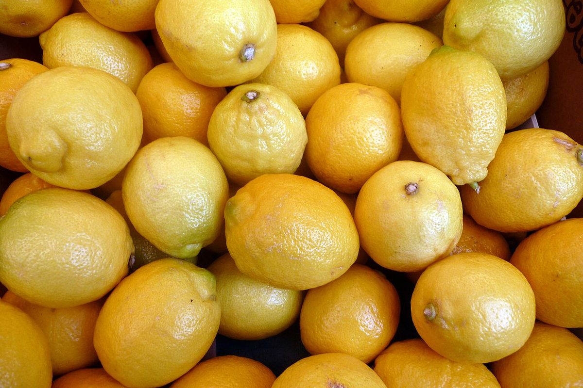 Montón de frutos cítricos amarillos apilados en un puesto de mercado.