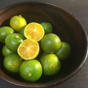 Frutos verdes en un tazón de madera, uno partido a la mitad.