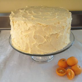 Un pastel cubierto de betún junto a unos frutos cítricos sobre un mantel.