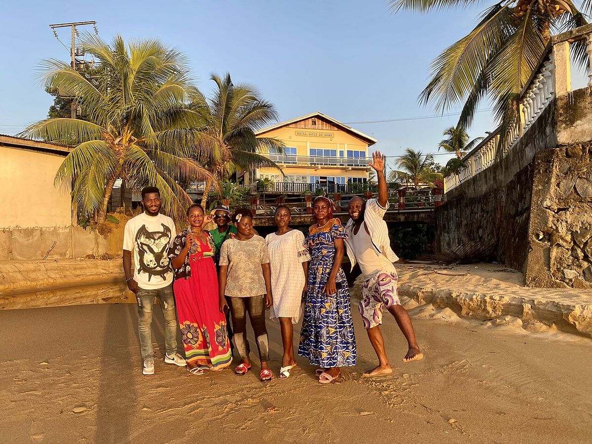 Un grupo de personas posando en una playa bordeada de palmas.