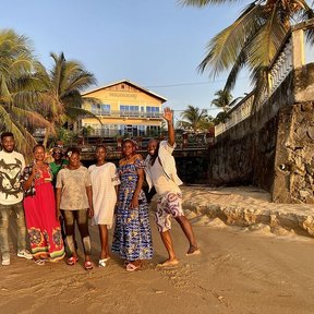 Un grupo de personas posando en una playa bordeada de palmas.
