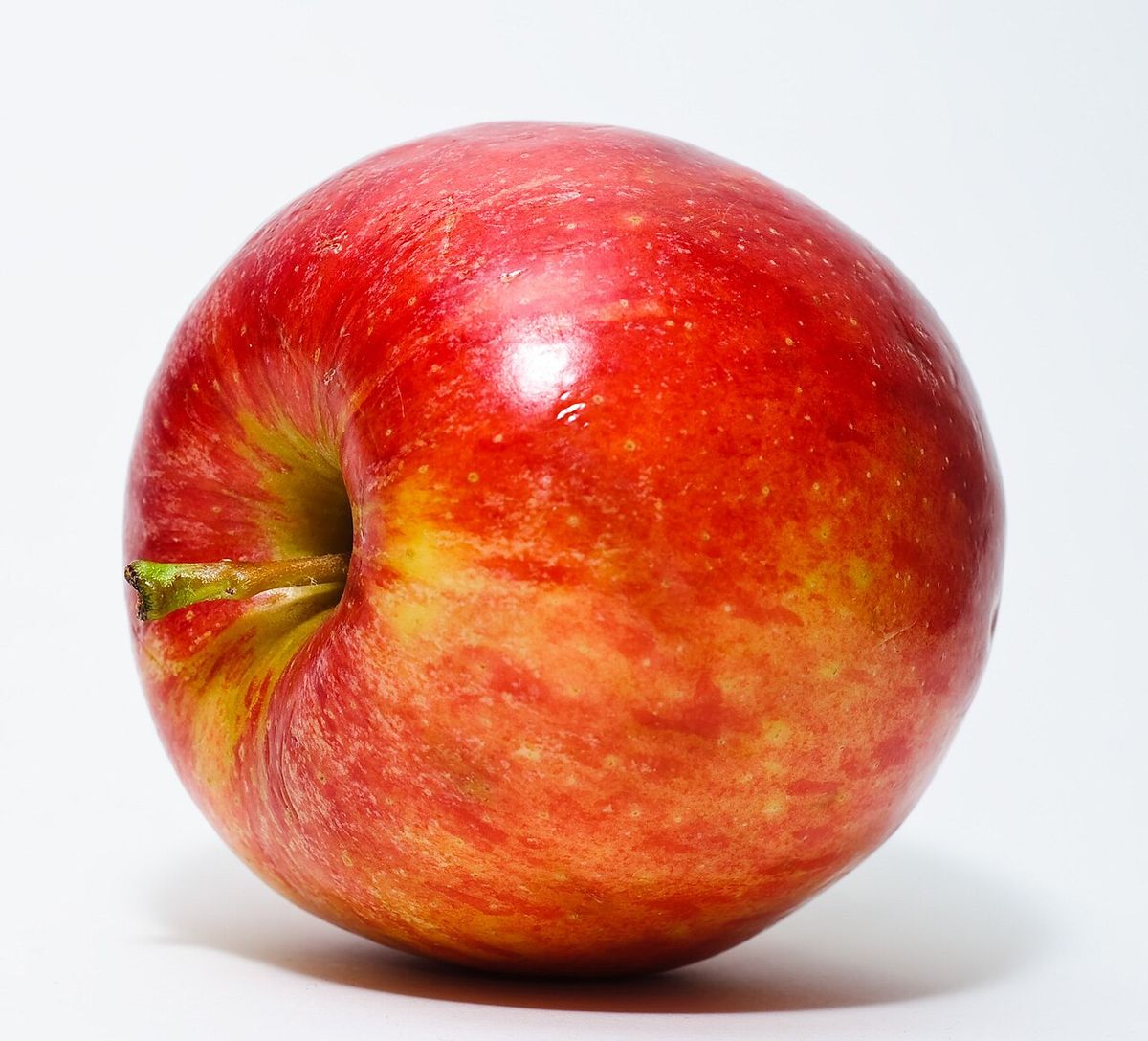 Una manzana roja y amarilla fotografiada sobre un fondo blanco.