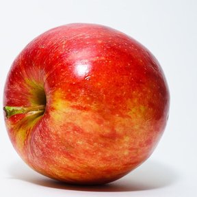 Una manzana roja y amarilla fotografiada sobre un fondo blanco.