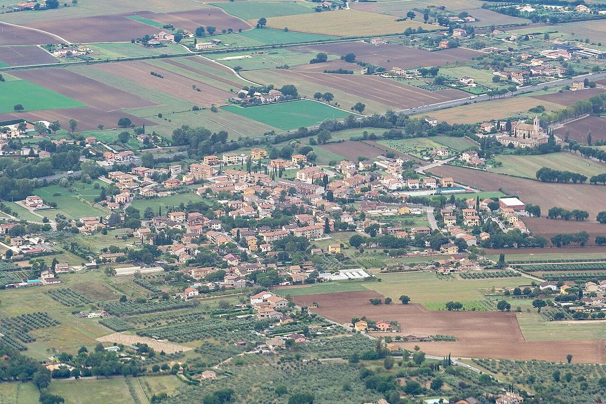 Vista aérea de un pueblo rodeado de campos de cultivo y olivares.