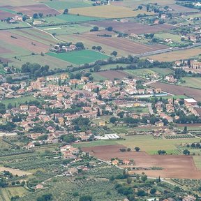 Vista aérea de un pueblo rodeado de campos de cultivo y olivares.