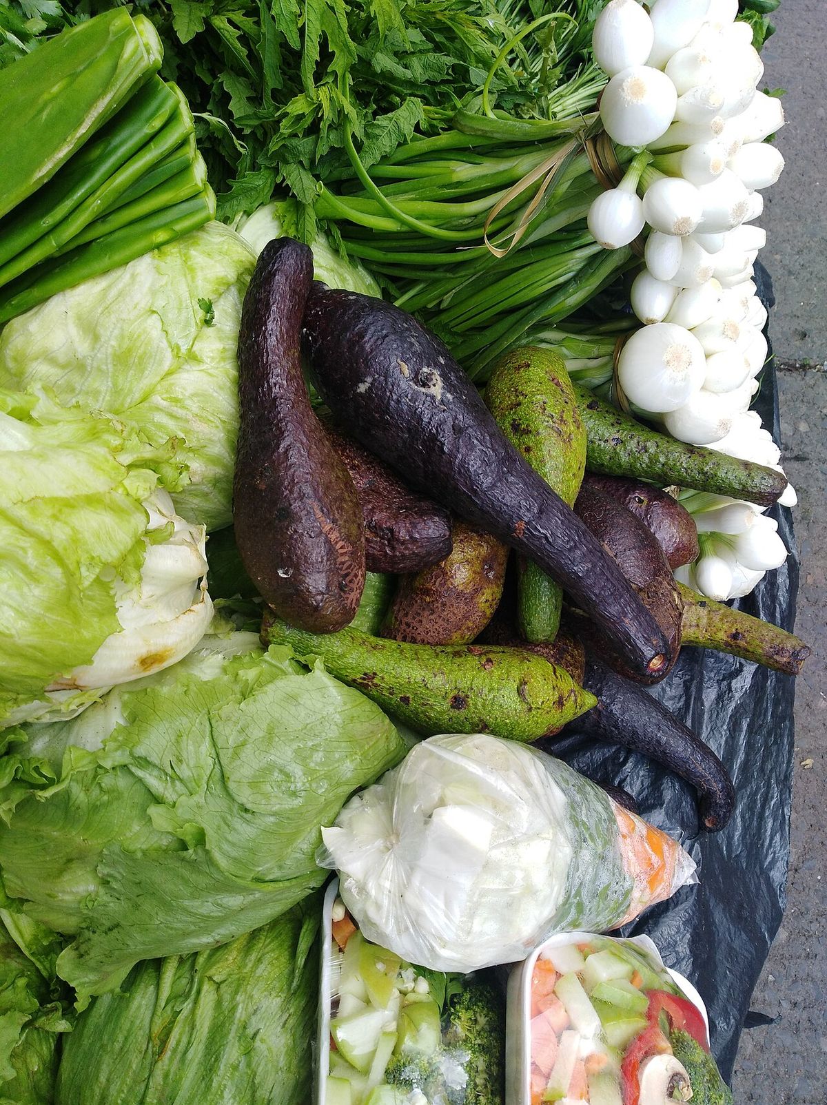 Puesto de verduras con chinines morados entre lechugas, cebollas y chiles.