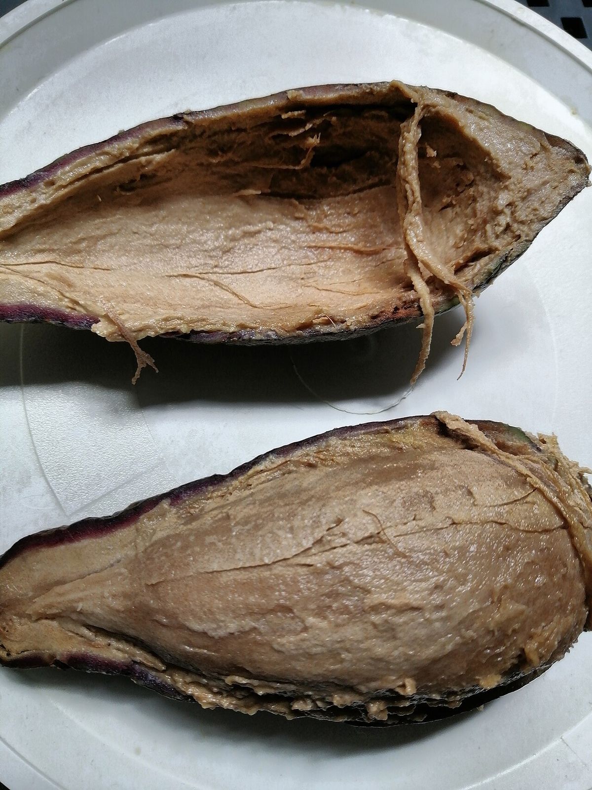 Dos mitades de chinine sobre un plato, con la cáscara morada y la pulpa clara.