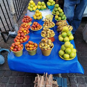 Puesto de fruta en la calle con rajas de ocote apiladas en el suelo.