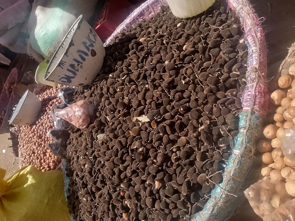 Canasto lleno de vainas de tamarindo en un puesto de mercado.